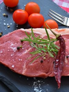 syrové červené maso na prkýnku s nástroji, kořením a zeleninou k přípravě masa